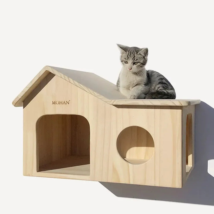 Wooden cat climbing frame with a house-shaped design, featuring multiple openings and a resting platform. A small kitten sits on top, enjoying the luxury wall-mounted cat shelf.